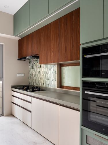 Modern galley kitchen with sage green cabinetry, walnut upper units, and mosaic tile backsplash