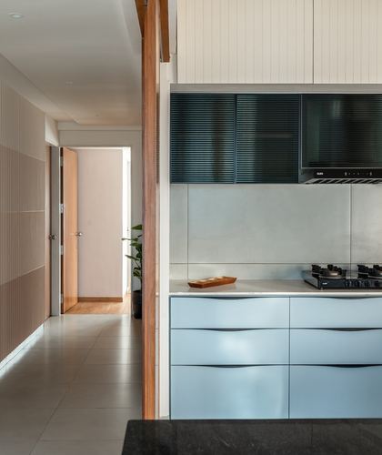Kitchen counter with pale blue drawers and louvered chimney, corridor visible beyond wooden column