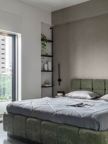 Minimalist bedroom with green tufted bed, textured wall, and black shelving niche by window