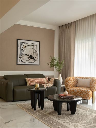 Living room with olive sofa, mustard patterned armchair, black marble coffee tables and abstract art