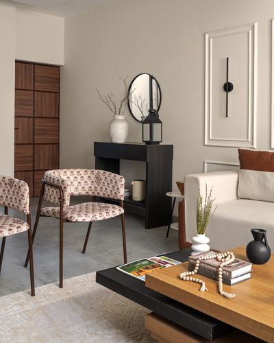 Living room with black console, round mirror, patterned chairs and wooden coffee table