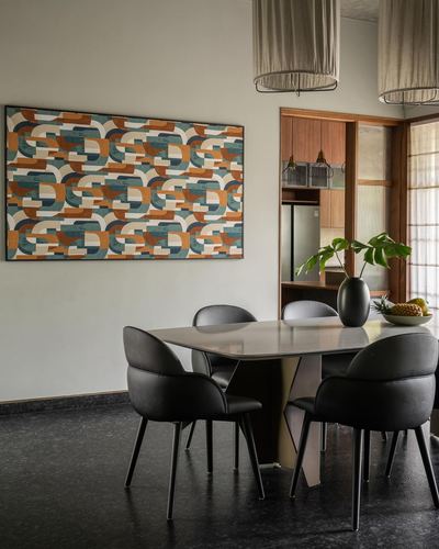 Dining area with black chairs, stone-top table, geometric wall art, terrazzo floor