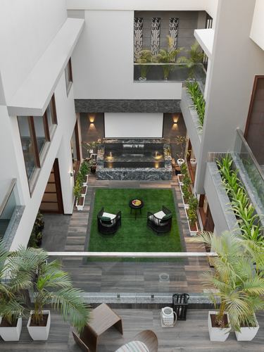 Aerial view of a double-height internal courtyard with water feature, turf lawn, seating, and layered balconies
