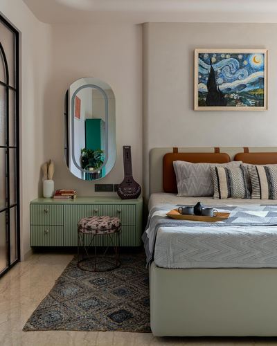 Sage green bedroom with oval mirror, tan leather headboard, and patterned rug