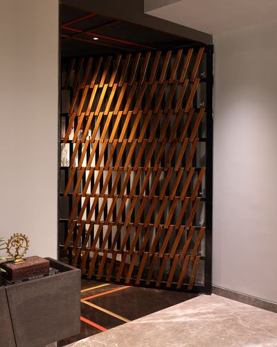 Foyer with diagonal wood trellis screen backlit by red light beside marble console with statue
