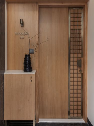 Entrance door of apartment 602 with wood paneling, brass grille strip, nameplate, and console with textured vase