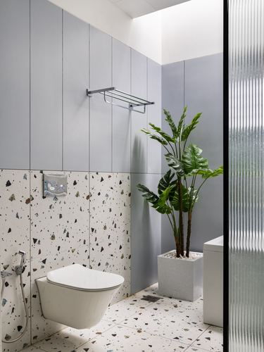 Bathroom with terrazzo lower walls, grey panelling, wall-hung toilet and reeded glass partition
