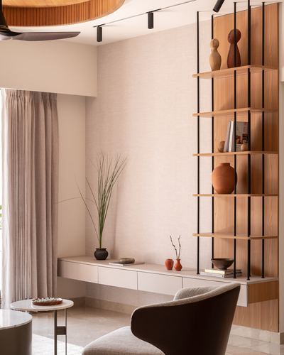 Wooden vertical shelving with ceramics beside a floating console and dark armchair in a warm-toned living room