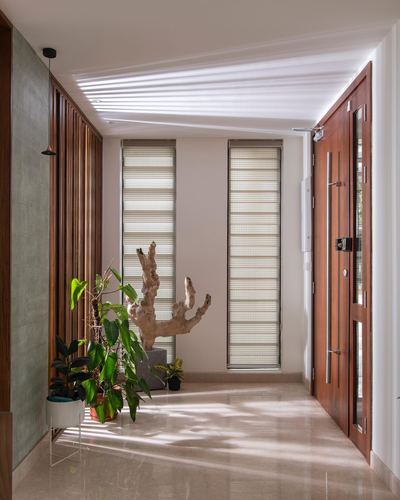Sunlit entry hallway with wooden slat screen, driftwood sculpture, and reddish wood door