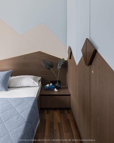 Bedroom corner with wood-panelled wardrobe wall, diamond hooks, and triangular painted headboard motif above bed