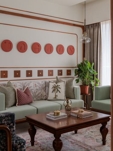 Living room with sage sofas, terracotta wall discs and wood-trimmed panel wall