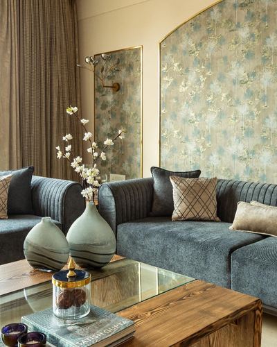 Grey-blue channel-tufted sofas around a wooden coffee table beneath an arched floral wallpaper panel