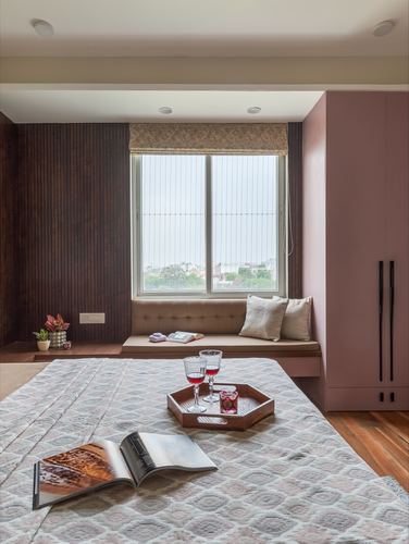 Bedroom with window seat, fluted wood wall, and pink wardrobe in daylight