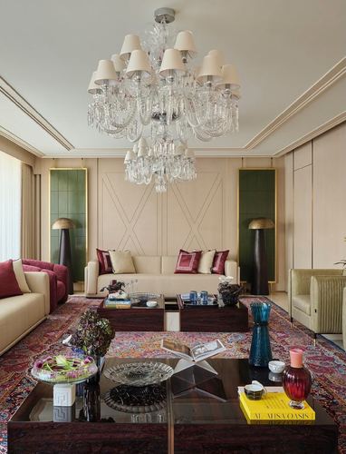 Formal majlis living room with tiered crystal chandelier, burgundy sofas, and patterned rug