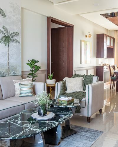 Living room with beige sofas, green marble coffee table, and botanical mural wall