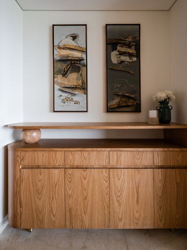 Wooden sideboard with drawers below a floating shelf, sphere leg, and two abstract art panels above