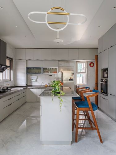 Contemporary grey kitchen with marble floor, white island, and blue upholstered wooden bar stools