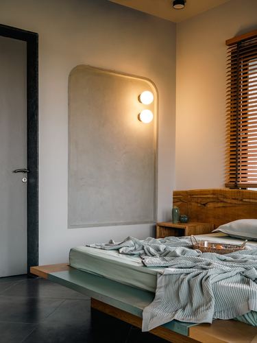 Bedroom corner with arched plaster niche, sphere sconces, and floating wooden platform bed