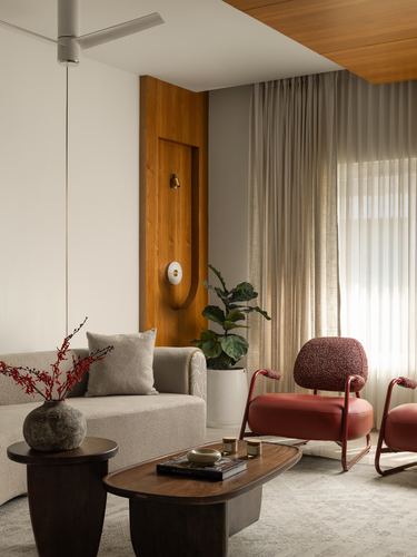 Living room with cream boucle sofa, red armchairs, arched wood wall niche and sheer curtains