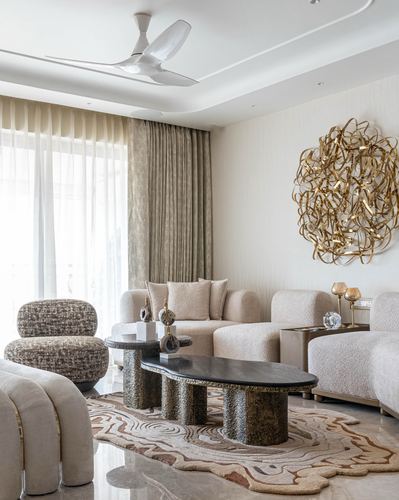Neutral living room with boucle sofas, sculptural stone coffee tables, and gold wall art