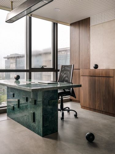 Green stone desk with black chair beside rain-streaked glass in wood-panelled office cabin