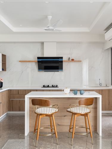Contemporary kitchen island with brass-legged wooden bar stools and marble-look backsplash