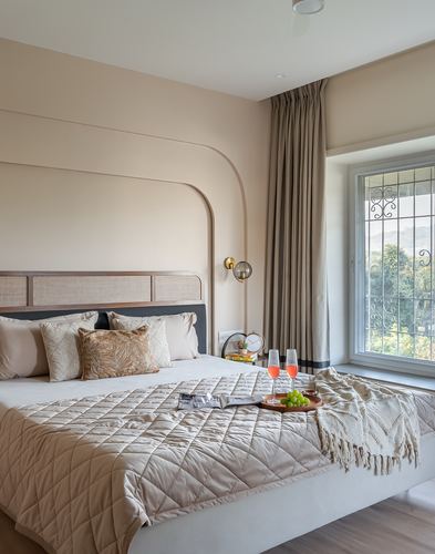 Beige bedroom with cane headboard, arched wall molding, and a breakfast tray on the bed near a window