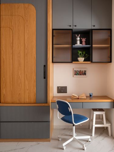 Kids study nook with wooden wardrobe, grey cabinetry, blue task chair, marble floor