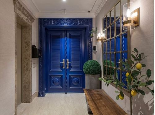 Entryway with carved blue double doors, marble floor, mirror, bench, and lemon tree
