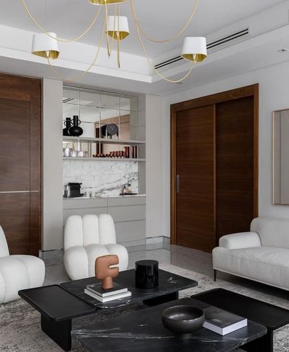 Modern living room with boucle sofas, black marble coffee tables, walnut sliding doors and gold chandelier