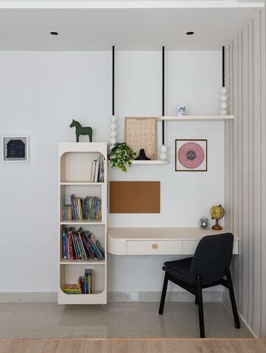 Children's study nook with floating desk, dark chair, bookshelf, and hanging shelf with framed art