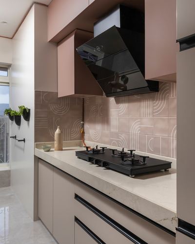 Pink-toned kitchen with black angular chimney hood over gas hob and patterned tile backsplash