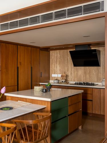 Wooden kitchen with stone backsplash, black chimney hood, and green-drawered island counter