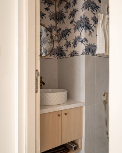 Small bathroom seen through open door with floral wallpaper, stone tile, and a textured vessel sink.