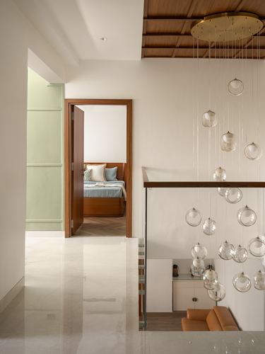 Landing with marble floor, wood-clad ceiling, glass balustrade, and hanging bubble pendant lights over a stairwell