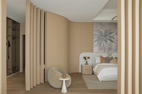 Bedroom with curved fluted wood partition, round bouclé chair, and palm mural above upholstered headboard