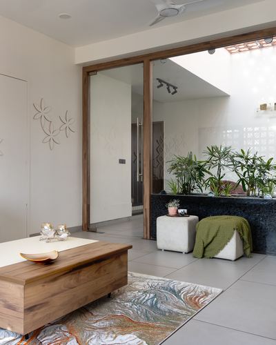 Living room with wooden trunk table opening through glass doors to a planted courtyard