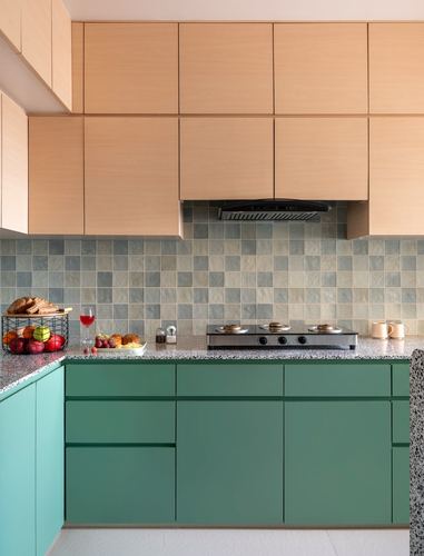Kitchen with peach wood upper cabinets, green lower cabinets, terrazzo counter and tiled backsplash