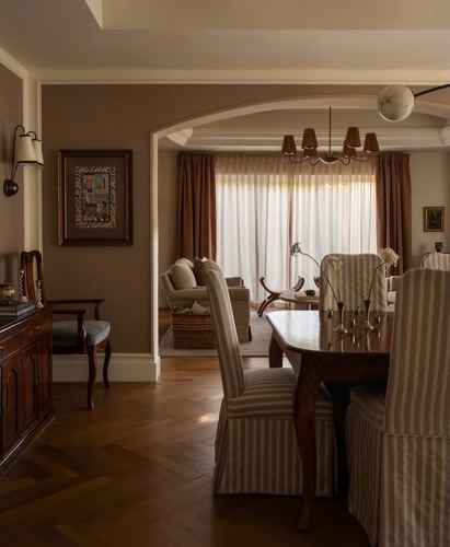 Dining room with striped chairs and dark wood table, arched opening to living room beyond