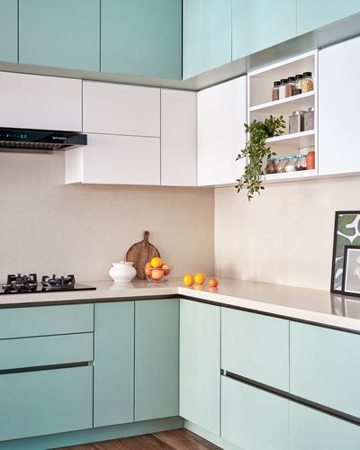 Corner kitchen with teal cabinetry, white countertop, open shelf and gas hob