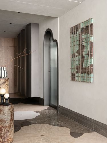 Foyer with arched door, curved grey cabinetry, textured wall art, and floral inlaid stone floor