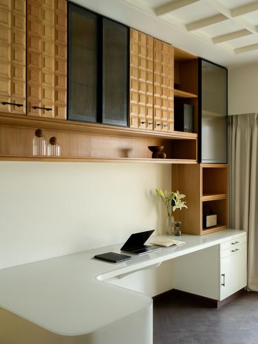Home office with carved wood cabinets, fluted glass doors, and a curved white desk