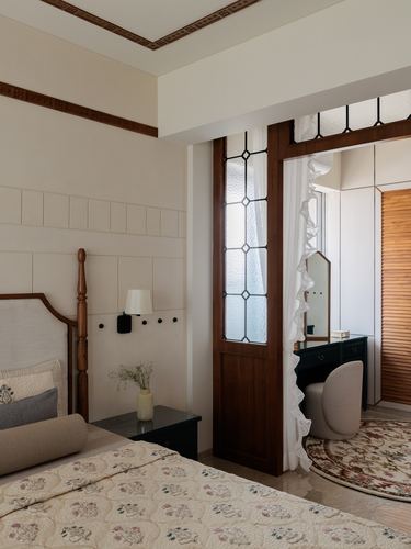 Bedroom with four-poster bed beside a stained-glass wooden door opening to a dressing area