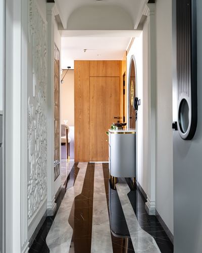 Corridor with striped marble floor, wood-paneled end wall, and console with arched mirror