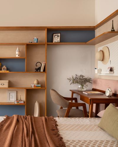 Bedroom corner with wooden display shelving, blue accent wall, and a small study desk with chair