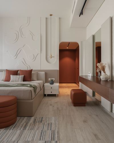 Bedroom with beige upholstered bed, terracotta pillows, sculpted plaster wall, and adjoining dressing console