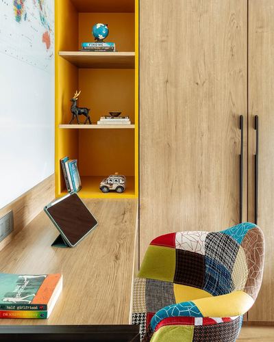 Study nook with mustard shelf, wood cabinetry, and patchwork armchair