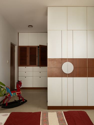 Bedroom corner with white and wood-toned built-in wardrobes, louvered cabinet, red rocking horse toy