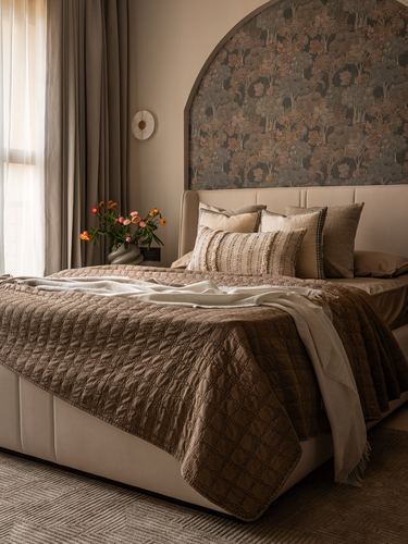 Bedroom with upholstered bed, quilted brown throw, and arched forest-print wallpaper behind headboard