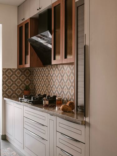 Kitchen counter with gas stove, patterned tile backsplash, and wooden overhead cabinets with chimney hood